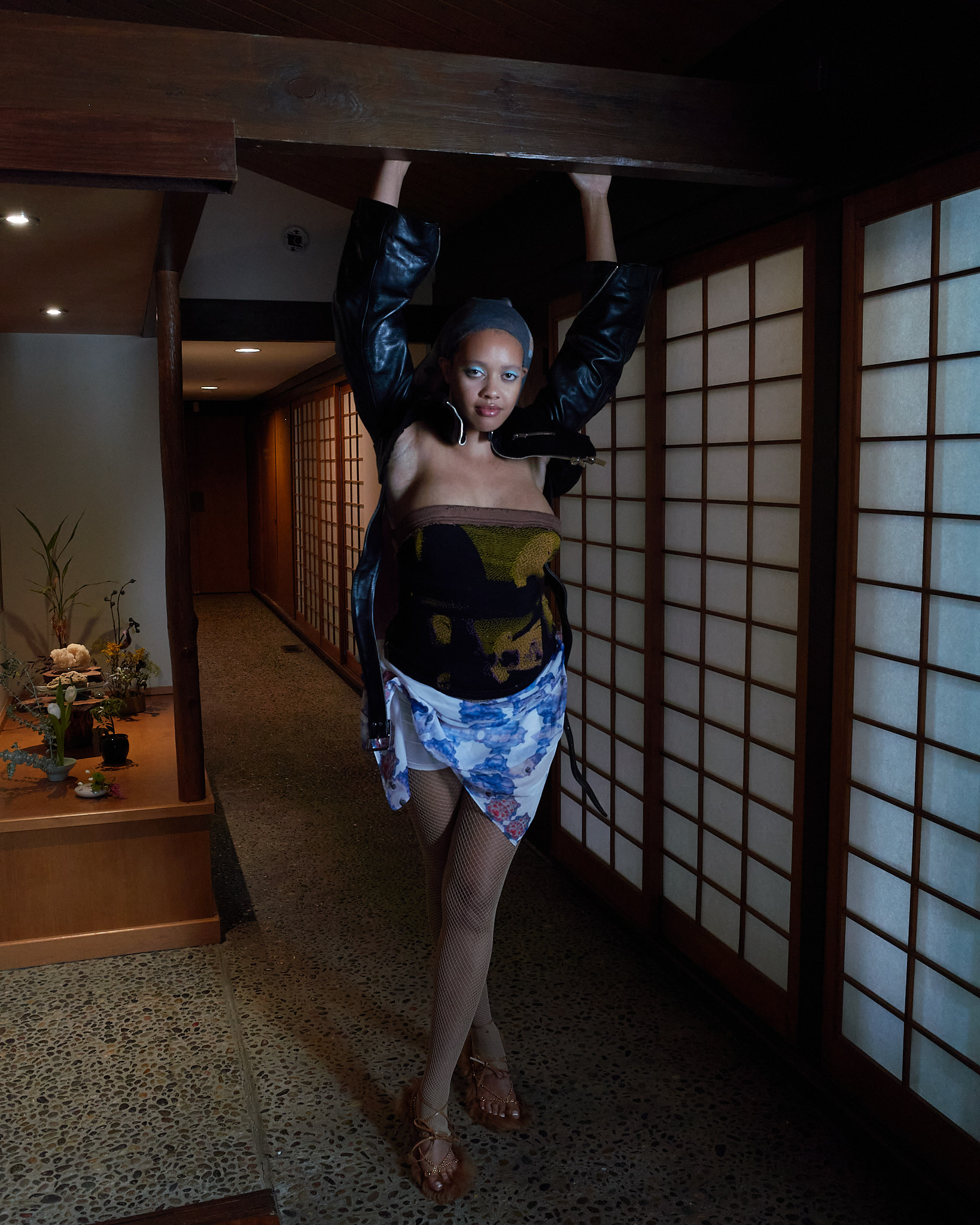 Female model standing with hands outstretched towards a ceiling beam in a traditional japanese house looking toward the camera